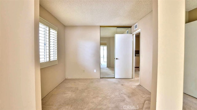 empty room with light carpet and a textured ceiling