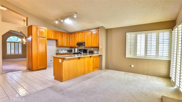 kitchen with kitchen peninsula, a textured ceiling, light tile patterned flooring, and sink