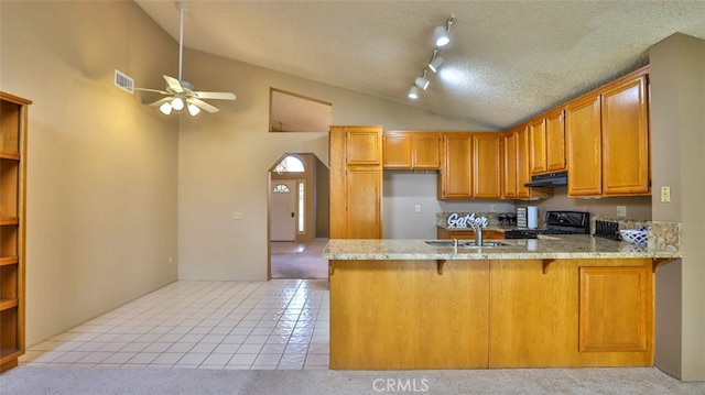 kitchen featuring kitchen peninsula, black stove, light tile patterned floors, and sink