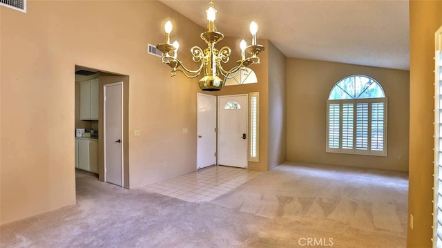 foyer entrance featuring light carpet, high vaulted ceiling, and a chandelier