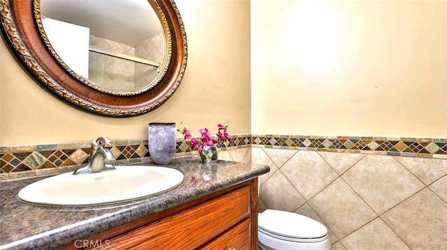 bathroom with tile patterned flooring, vanity, toilet, and tile walls