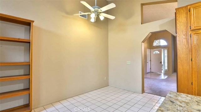 interior space with ceiling fan, light colored carpet, a textured ceiling, and high vaulted ceiling