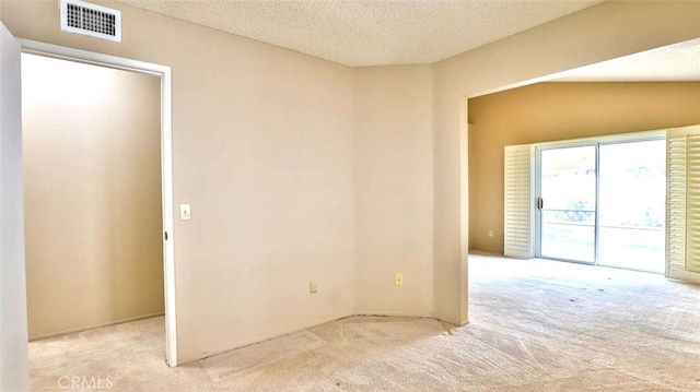 unfurnished room featuring a textured ceiling, light carpet, and vaulted ceiling