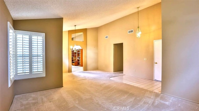 carpeted spare room featuring high vaulted ceiling, a chandelier, and a textured ceiling