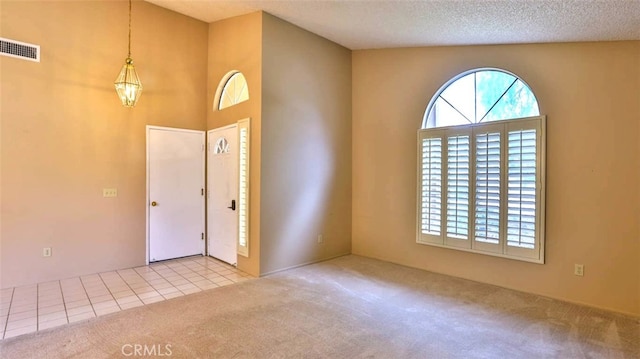 carpeted entrance foyer featuring a towering ceiling and a textured ceiling