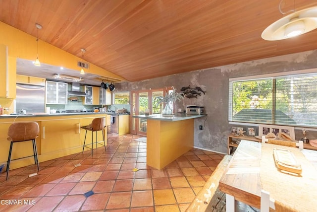 kitchen featuring decorative light fixtures, a breakfast bar area, kitchen peninsula, wooden ceiling, and high end fridge