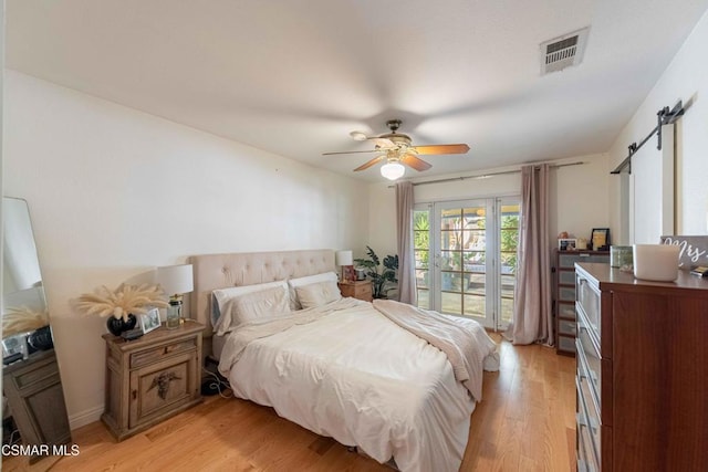 bedroom featuring light wood-type flooring, ceiling fan, and a barn door