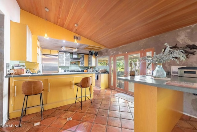 kitchen featuring wood ceiling, built in refrigerator, kitchen peninsula, and a breakfast bar area