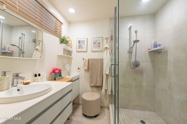 bathroom with a shower with door, tile patterned floors, and vanity