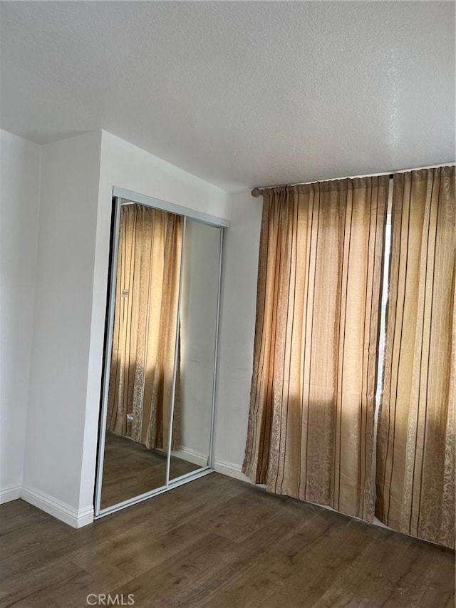 spare room with a textured ceiling and dark wood-type flooring