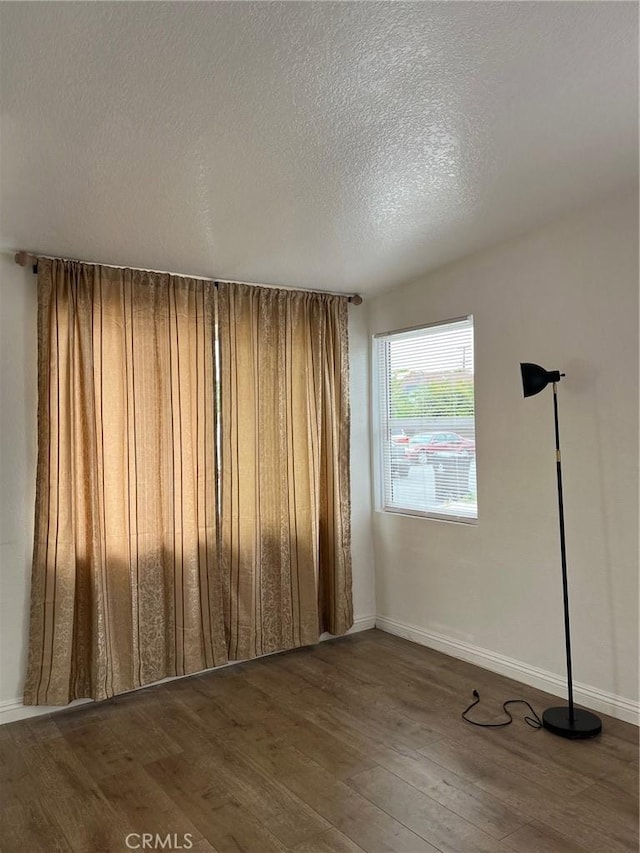 spare room with dark hardwood / wood-style flooring and a textured ceiling