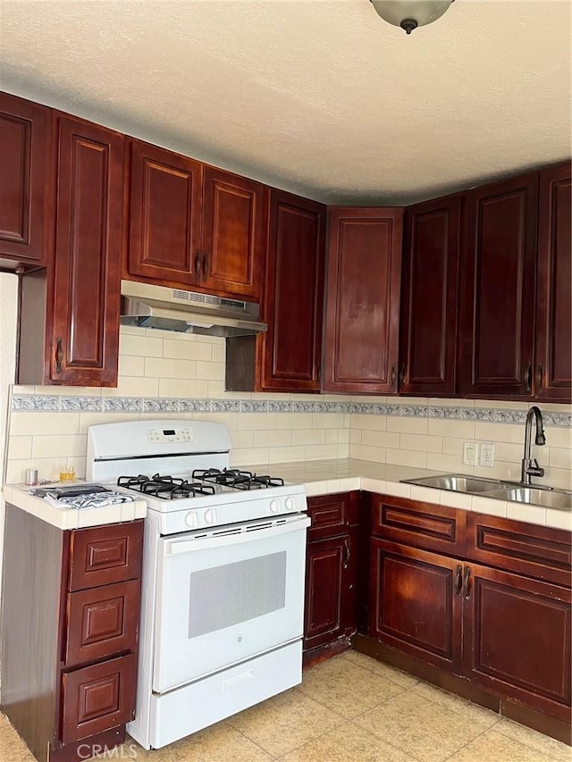 kitchen featuring a textured ceiling, decorative backsplash, white gas range, and sink