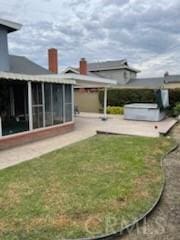 view of yard featuring a sunroom, a patio, and a hot tub