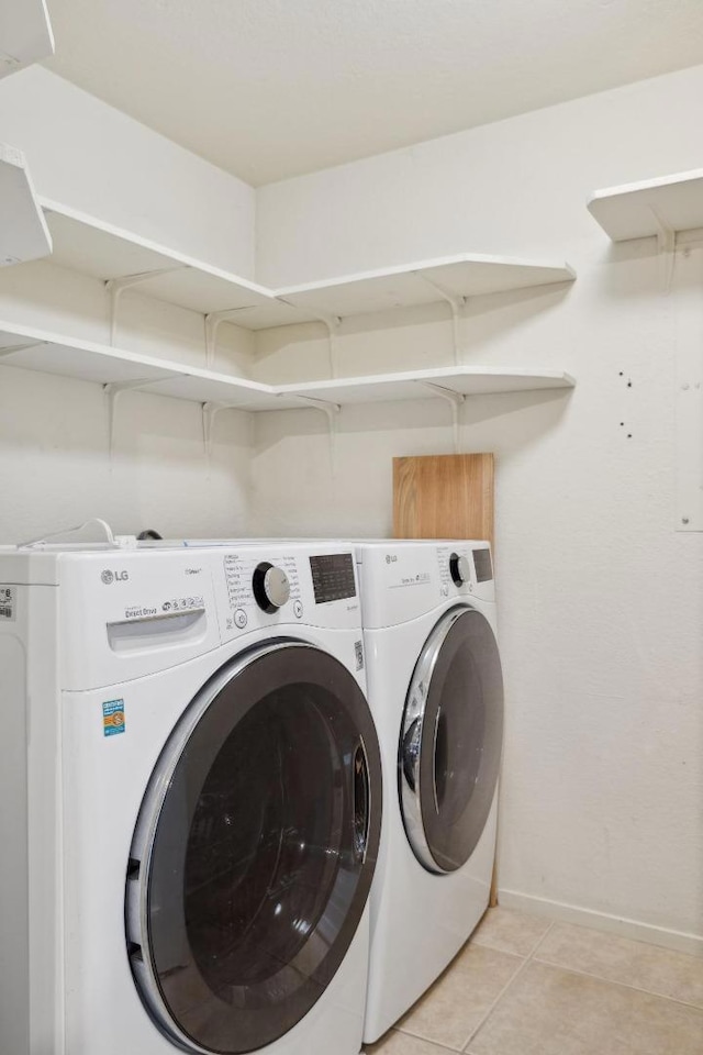 clothes washing area with independent washer and dryer and light tile patterned flooring