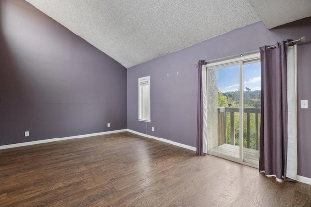 empty room featuring dark wood-type flooring, vaulted ceiling, and a textured ceiling