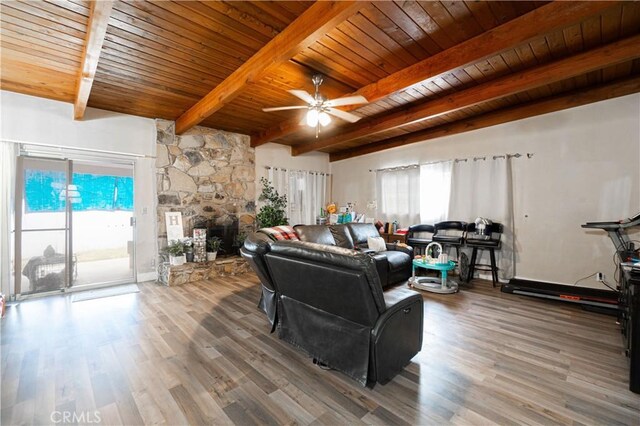 living room featuring a stone fireplace, ceiling fan, beam ceiling, wood-type flooring, and wood ceiling