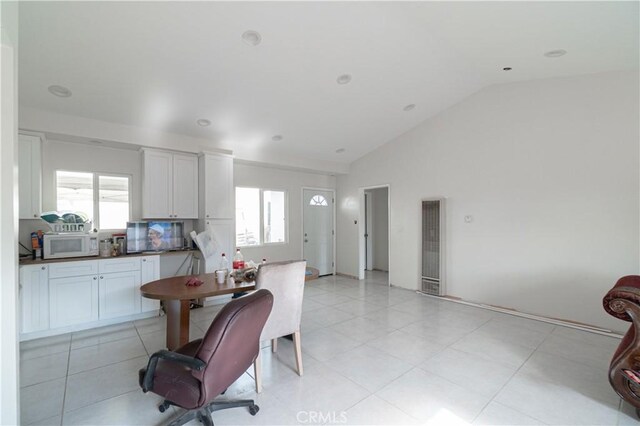 kitchen featuring light tile patterned floors, vaulted ceiling, white cabinetry, and a healthy amount of sunlight