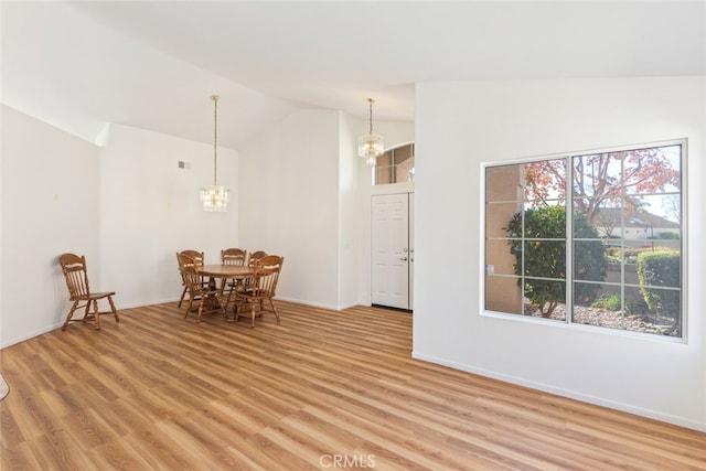 dining space featuring a chandelier, light wood-type flooring, and lofted ceiling