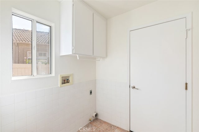 clothes washing area with cabinets, washer hookup, electric dryer hookup, light tile patterned floors, and tile walls