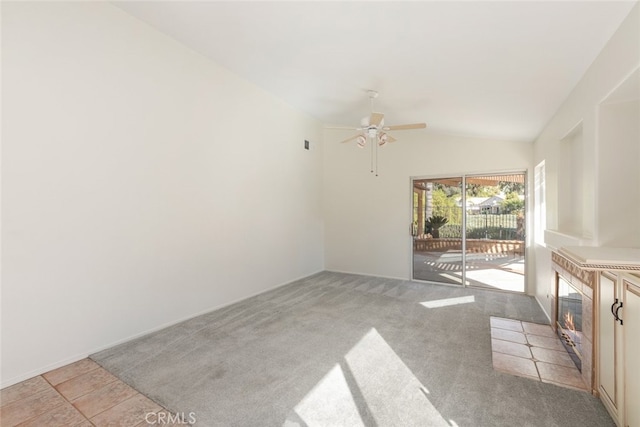 unfurnished living room featuring light carpet, vaulted ceiling, ceiling fan, and a tiled fireplace