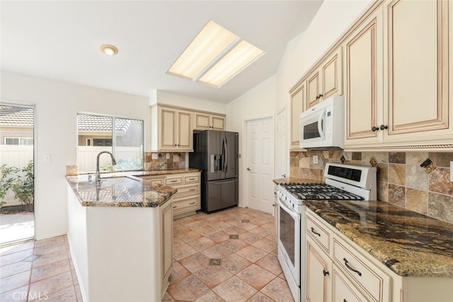 kitchen with decorative backsplash, white appliances, and dark stone counters