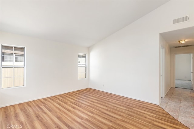 spare room with light hardwood / wood-style floors, vaulted ceiling, and a healthy amount of sunlight