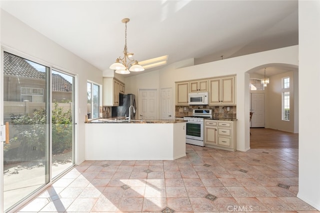 kitchen with white appliances, hanging light fixtures, decorative backsplash, a notable chandelier, and kitchen peninsula