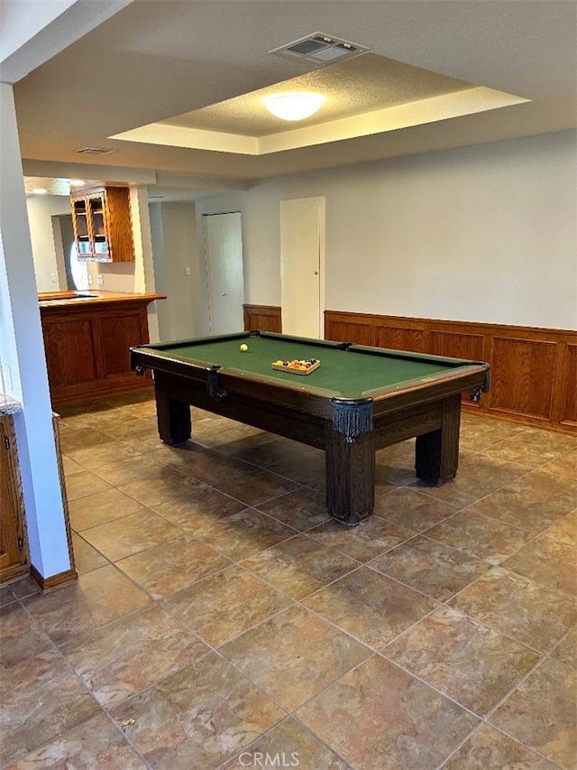 game room featuring wood walls, pool table, and a tray ceiling