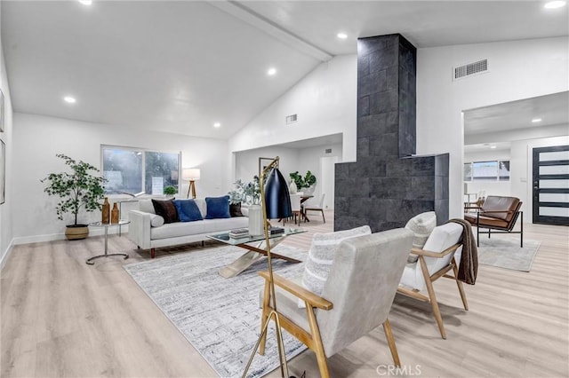 living room featuring beam ceiling, light hardwood / wood-style floors, and high vaulted ceiling