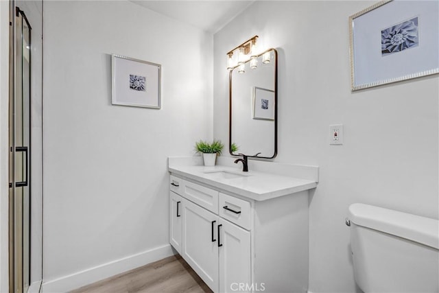 bathroom with hardwood / wood-style floors, vanity, and toilet