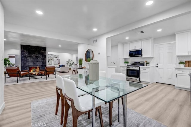 dining room featuring a fireplace and light hardwood / wood-style floors