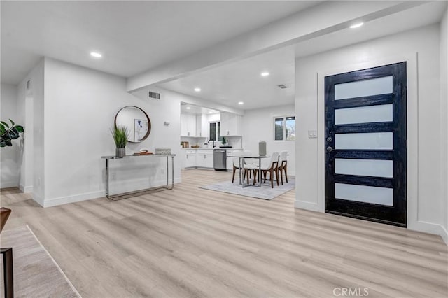 foyer featuring beamed ceiling and light hardwood / wood-style flooring