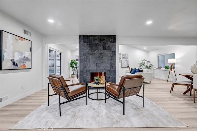 living room featuring a tile fireplace and light hardwood / wood-style flooring