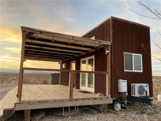 back house at dusk featuring ac unit and a deck