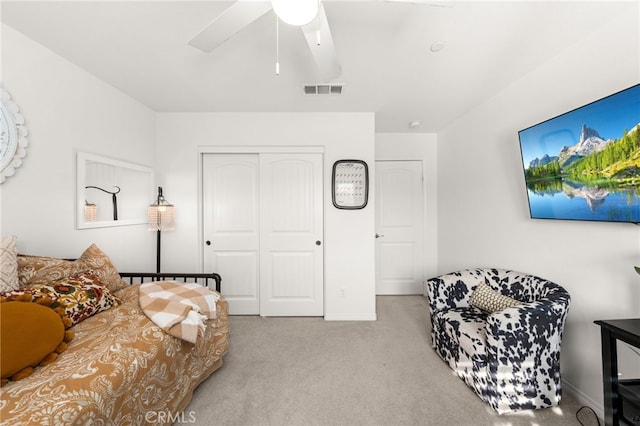 bedroom with ceiling fan, light carpet, and a closet