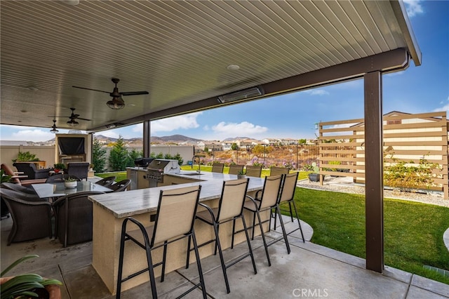 view of patio with a mountain view, an outdoor bar, ceiling fan, and a grill