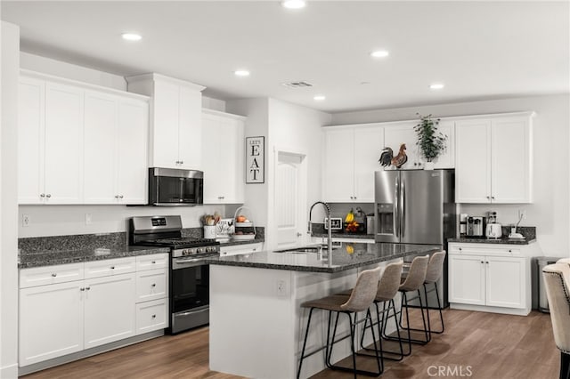 kitchen featuring stainless steel appliances, a kitchen island with sink, dark wood-type flooring, sink, and white cabinetry