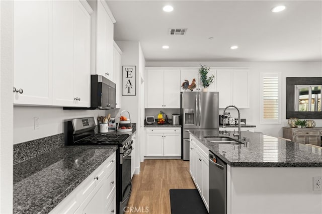 kitchen with an island with sink, stainless steel appliances, white cabinetry, and sink