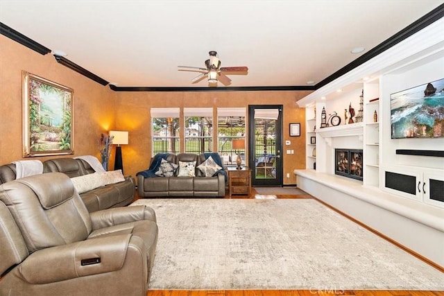 living room with ceiling fan, built in features, light hardwood / wood-style floors, and ornamental molding