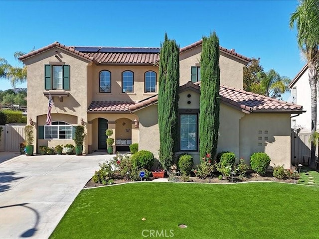 mediterranean / spanish house with a front yard and solar panels