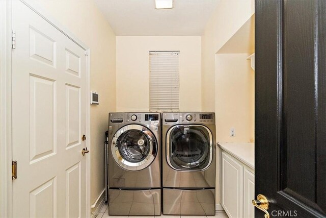 clothes washing area featuring cabinets, light tile patterned floors, and washer and dryer