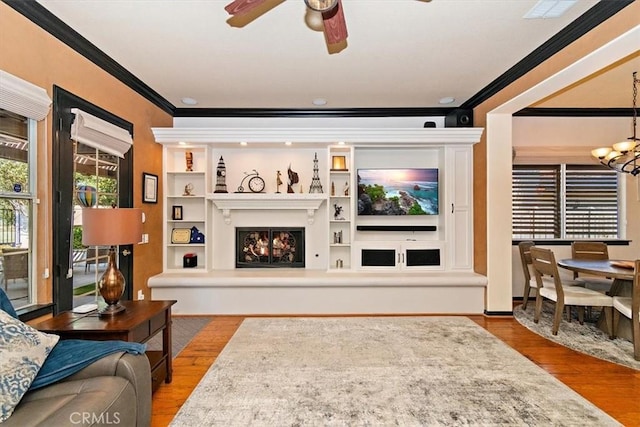 living room featuring ceiling fan with notable chandelier, light wood-type flooring, and crown molding