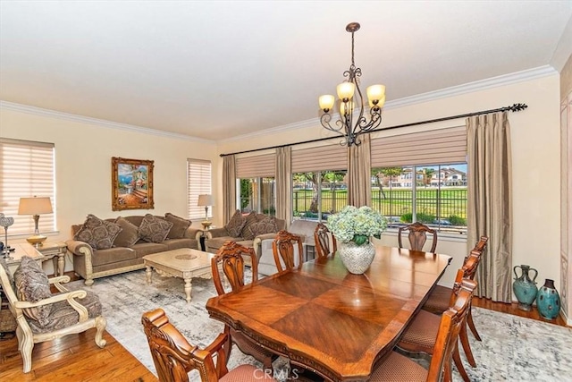 dining space featuring hardwood / wood-style flooring, crown molding, and an inviting chandelier