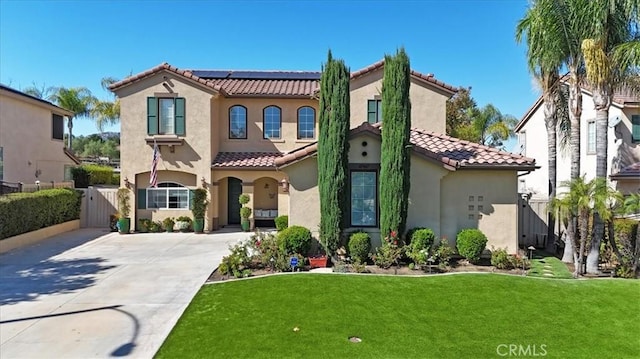 mediterranean / spanish-style home featuring solar panels and a front lawn