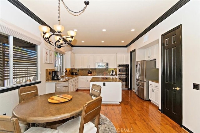 kitchen featuring white cabinetry, sink, light hardwood / wood-style flooring, a chandelier, and appliances with stainless steel finishes