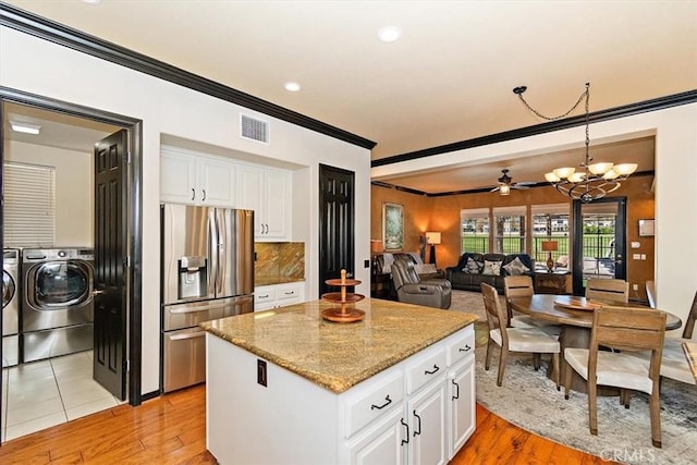 kitchen with a center island, stainless steel fridge, decorative light fixtures, light hardwood / wood-style floors, and white cabinetry