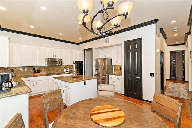 kitchen featuring a center island, stainless steel appliances, light hardwood / wood-style flooring, a notable chandelier, and white cabinets