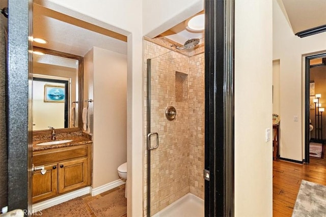 bathroom with toilet, vanity, an enclosed shower, and hardwood / wood-style flooring