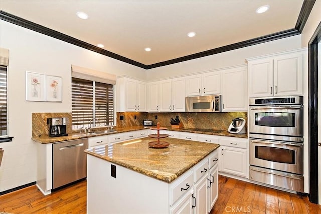 kitchen featuring a center island, white cabinets, light wood-type flooring, and appliances with stainless steel finishes