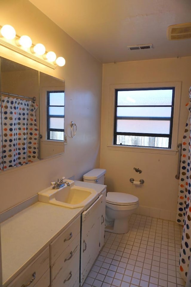 bathroom with toilet, a wealth of natural light, and tile patterned floors